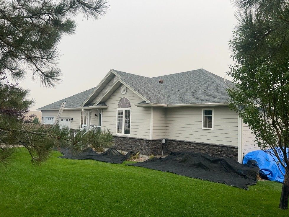 Woman in straw hat smiles, holding wine glass near a lake.