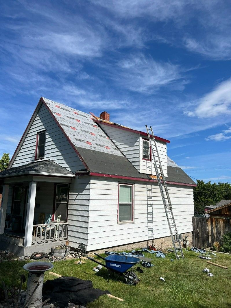 Woman in straw hat smiles, holding wine glass near a lake.