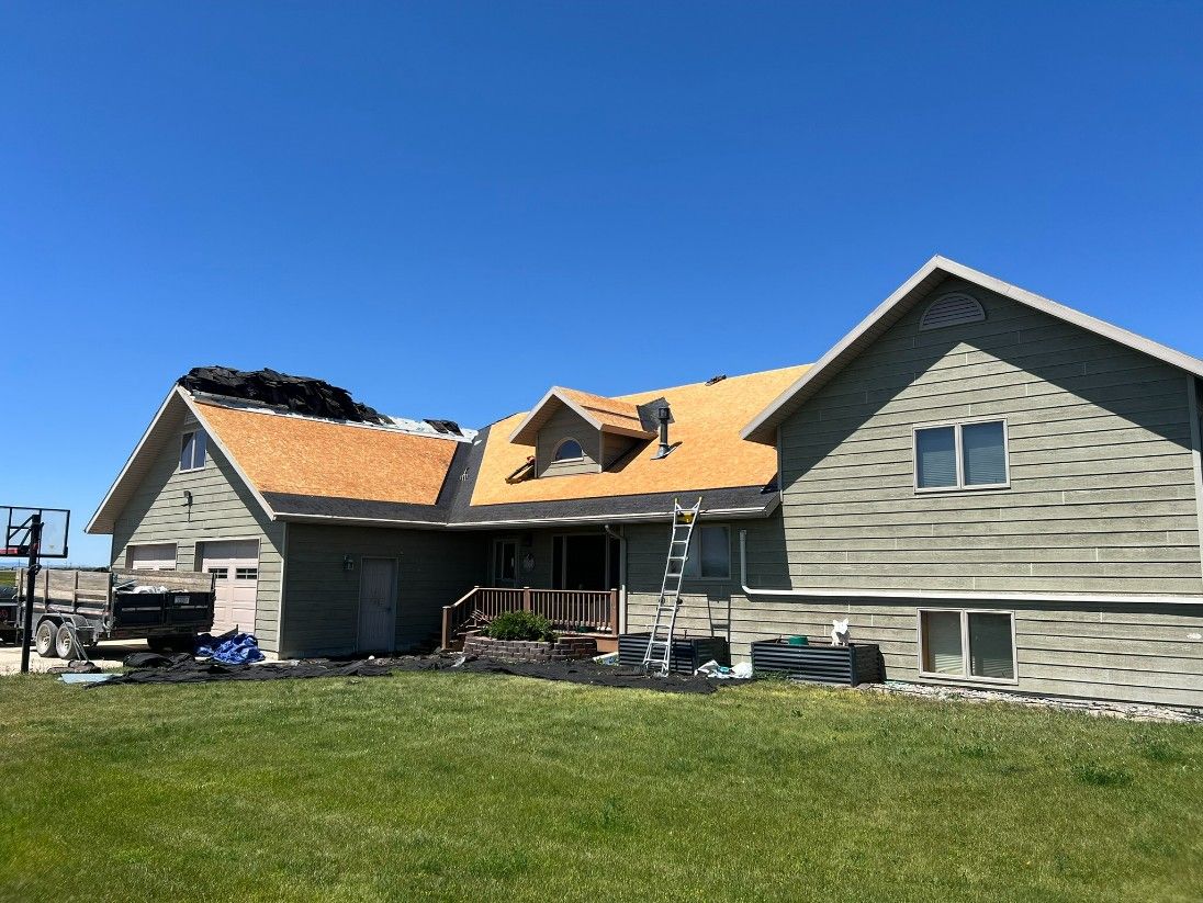 Woman in straw hat smiles, holding wine glass near a lake.
