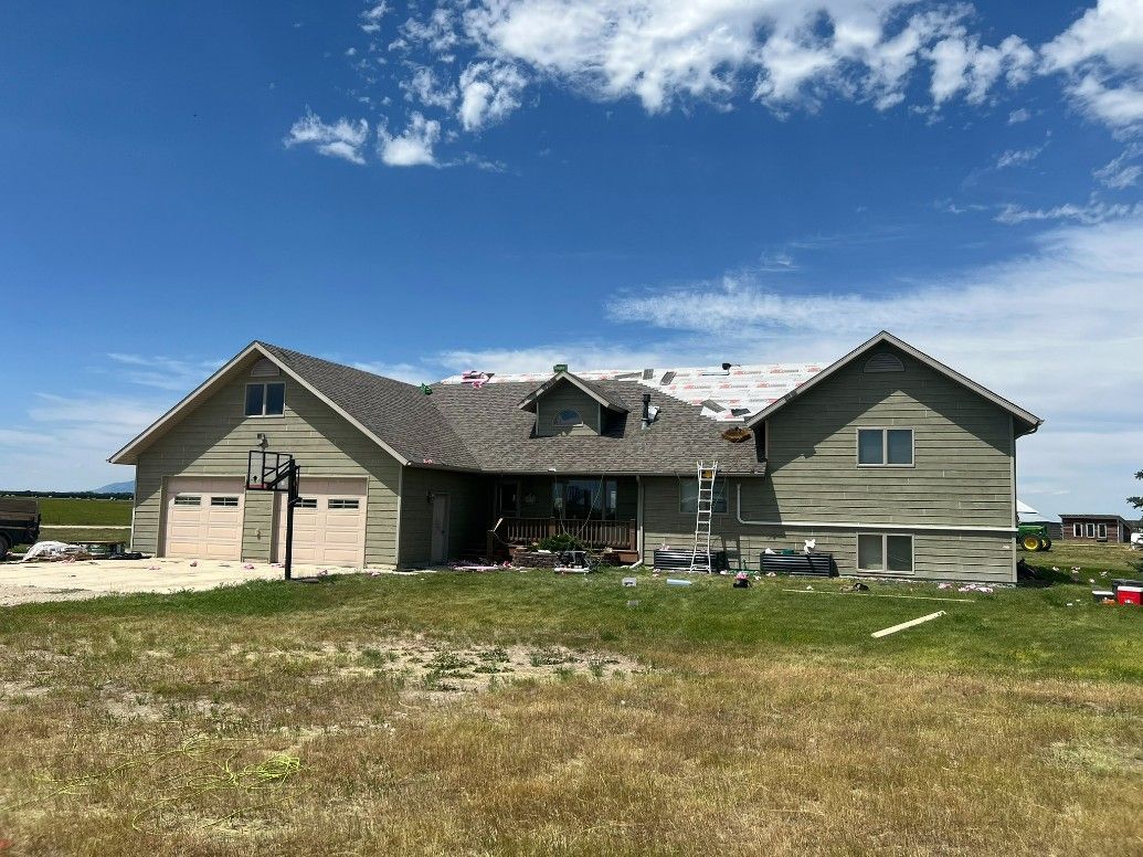 Woman in straw hat smiles, holding wine glass near a lake.