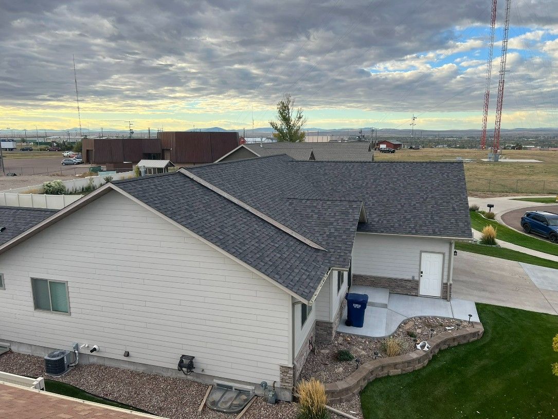 Woman in straw hat smiles, holding wine glass near a lake.