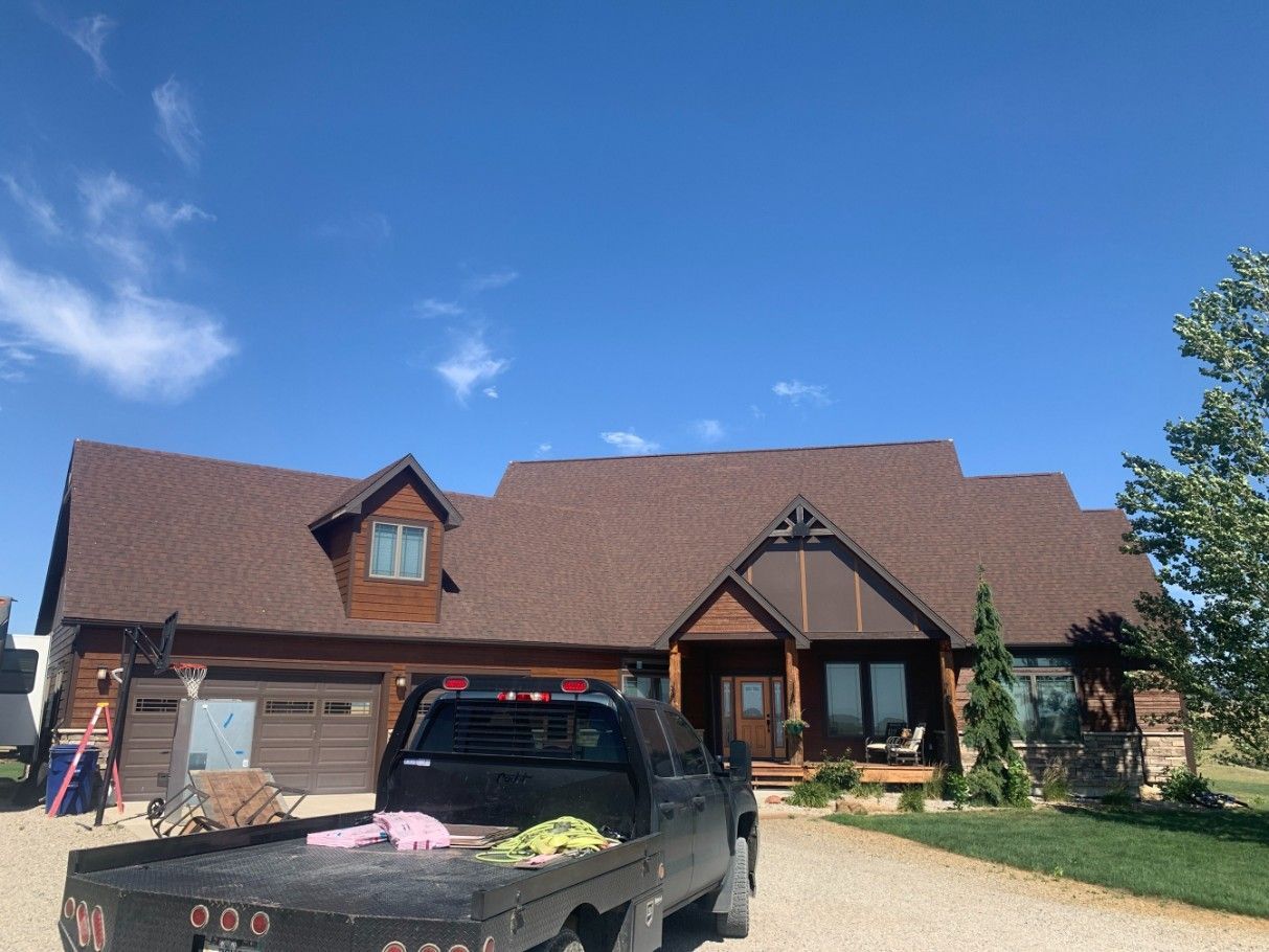 Woman in straw hat smiles, holding wine glass near a lake.