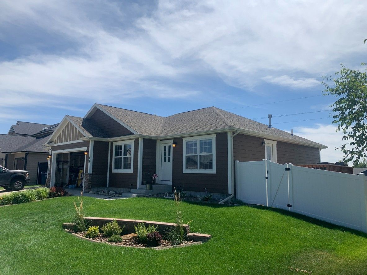 Woman in straw hat smiles, holding wine glass near a lake.