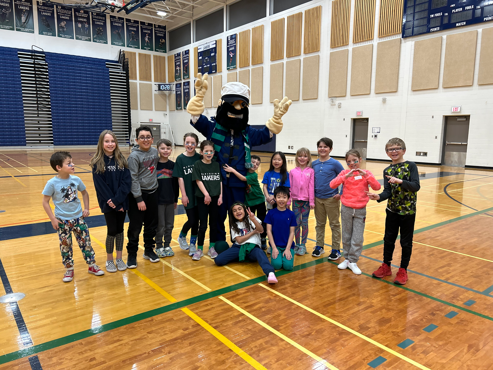 A group of children are posing for a picture with a mascot in a gym.