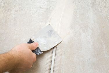 Worker Hands Using Spatula and Plastering Wall — Painters in Parkes