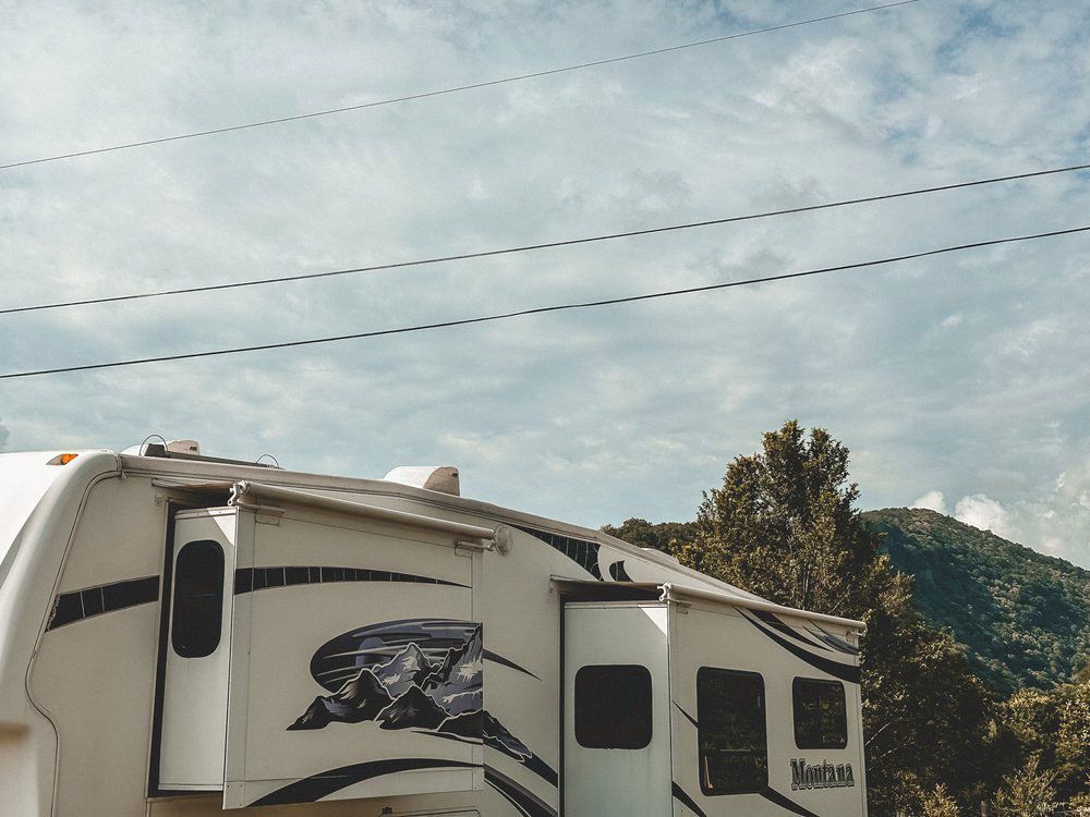 A white rv is parked in front of a mountain.