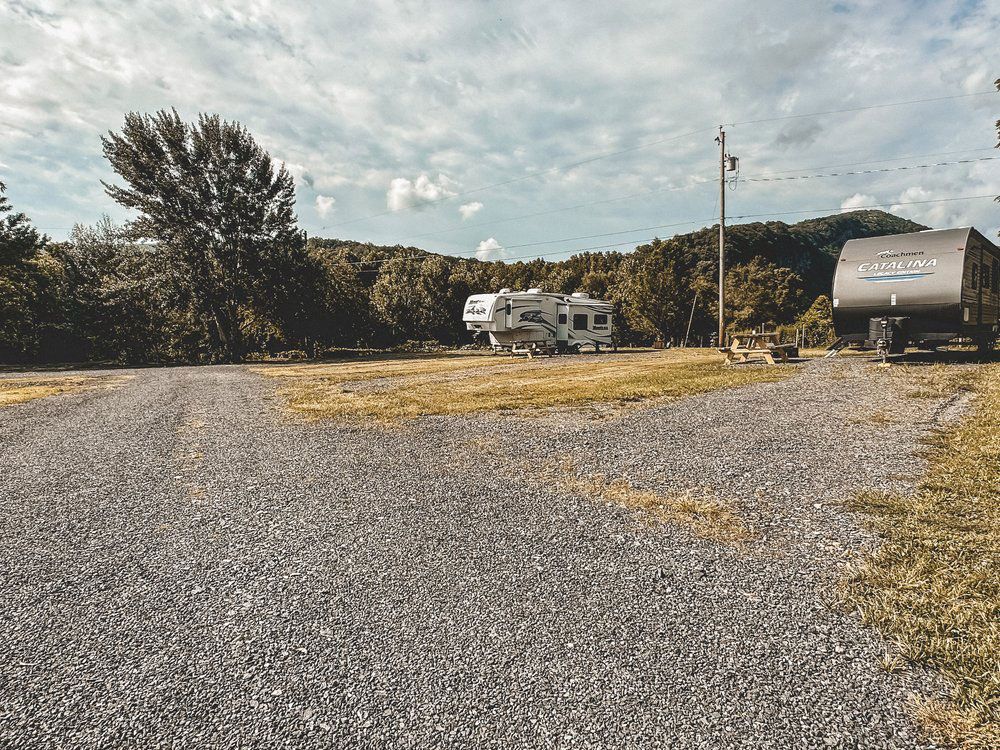 A couple of rvs are parked on the side of a gravel road.