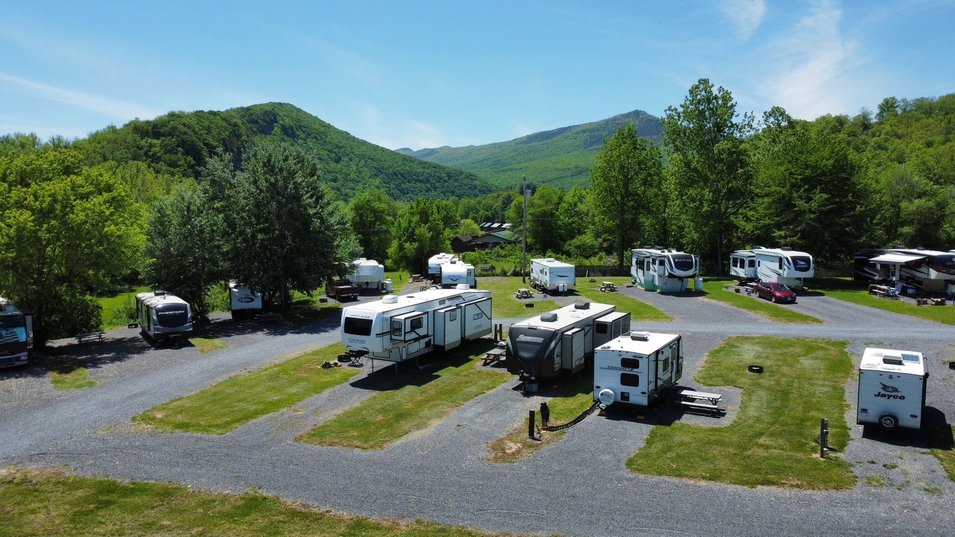 A bunch of rvs are parked in a lot with mountains in the background.