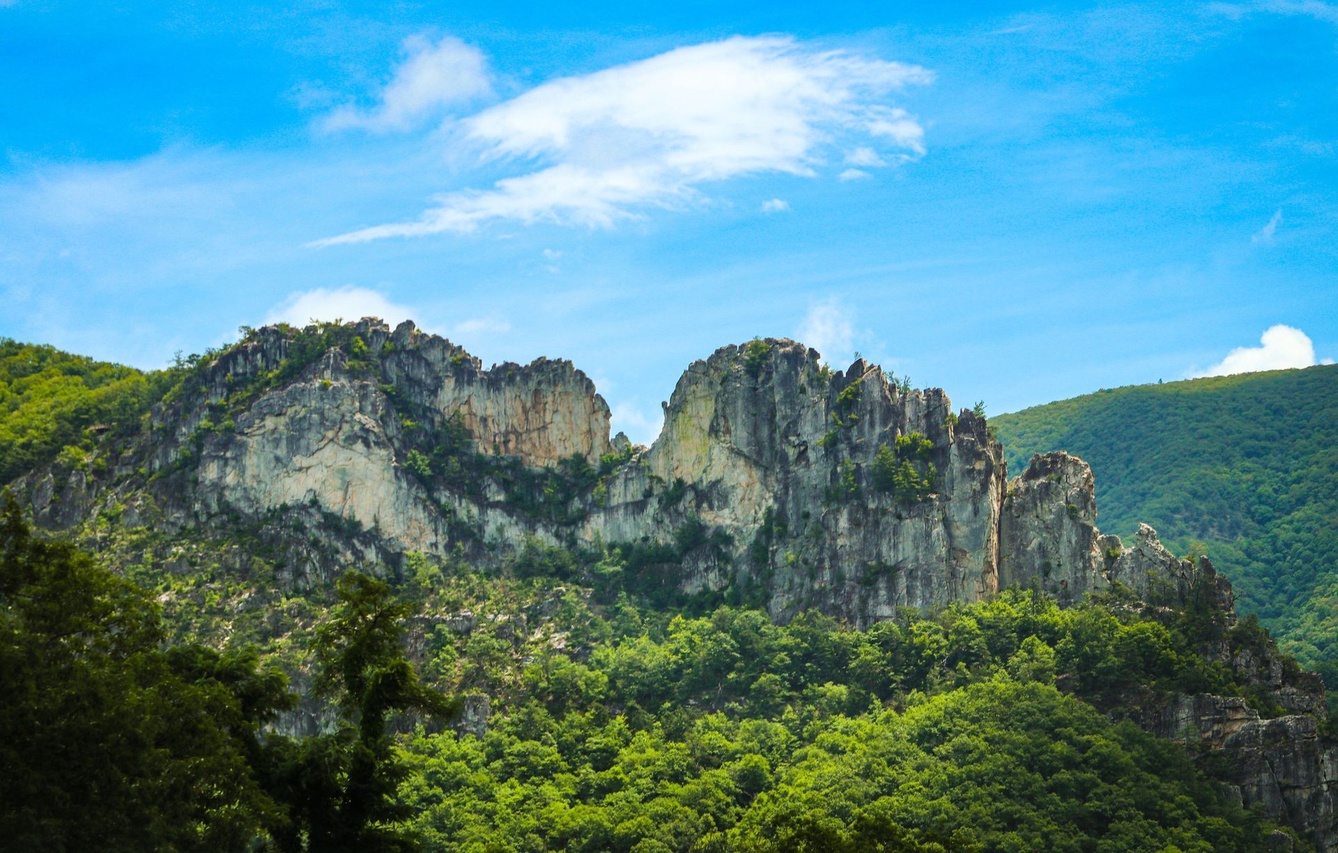 A mountain covered in trees and rocks with a blue sky in the background.