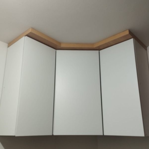 Tres armarios blancos cuelgan del techo en una cocina.