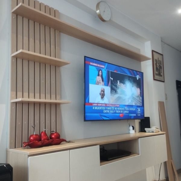 Un televisor de pantalla plana está montado en una pared sobre un centro de entretenimiento de madera.