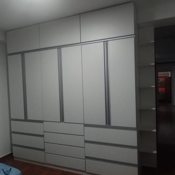 Un dormitorio con muchos armarios y cajones blancos.