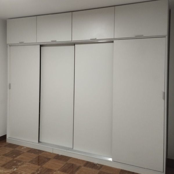 Un gran armario blanco con puertas correderas en un dormitorio.