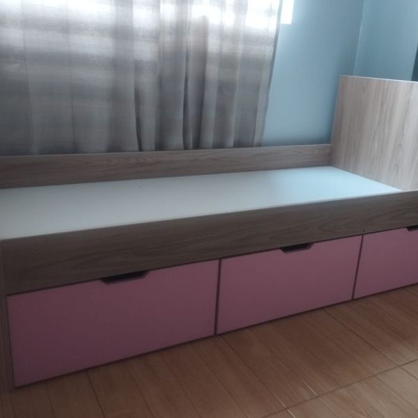Una cama con cajones rosas debajo en un dormitorio.