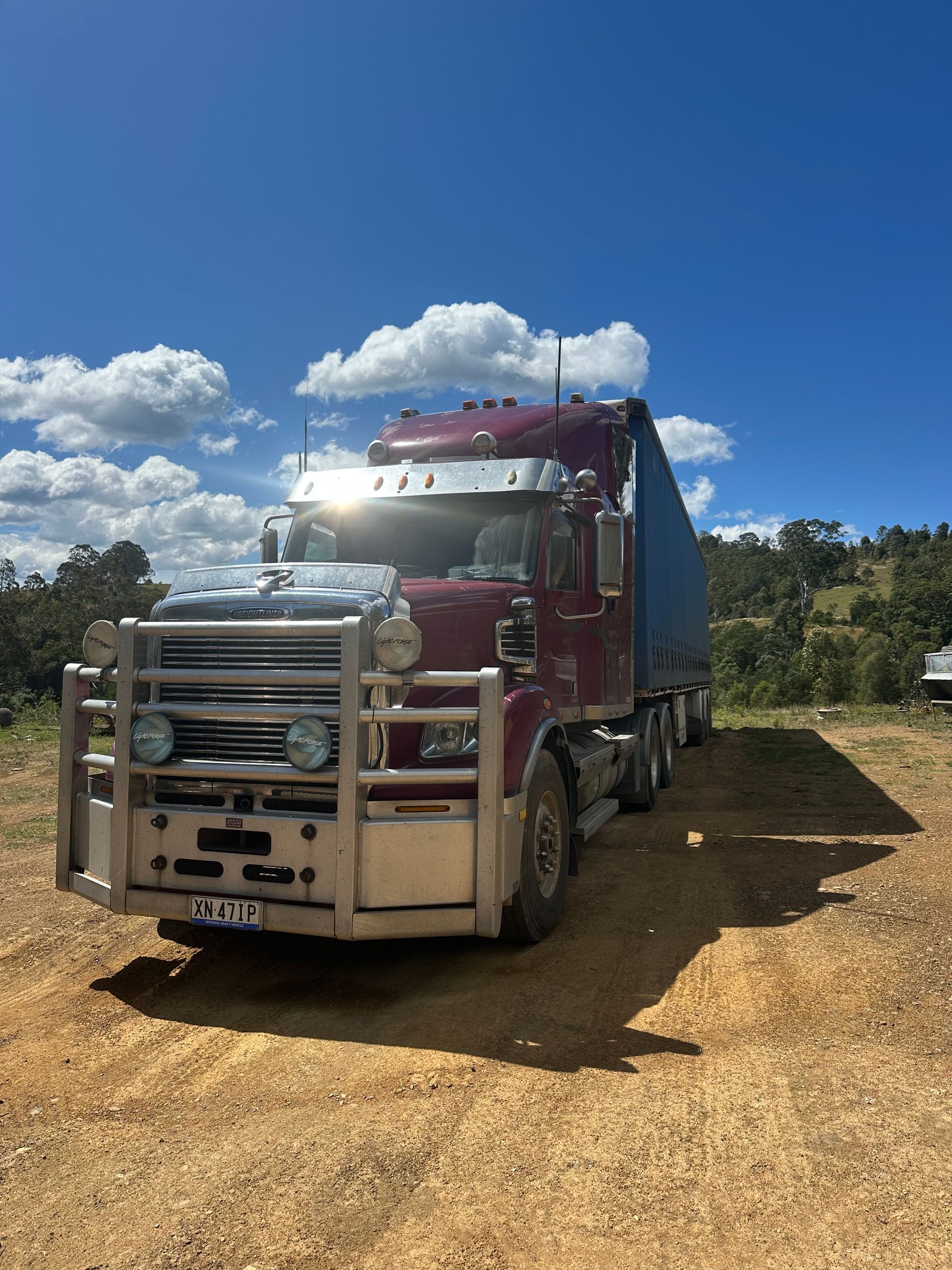 Maroon semi-truck parked on a dirt road — D & M Freighters Water In Bucca Wauka, NSW