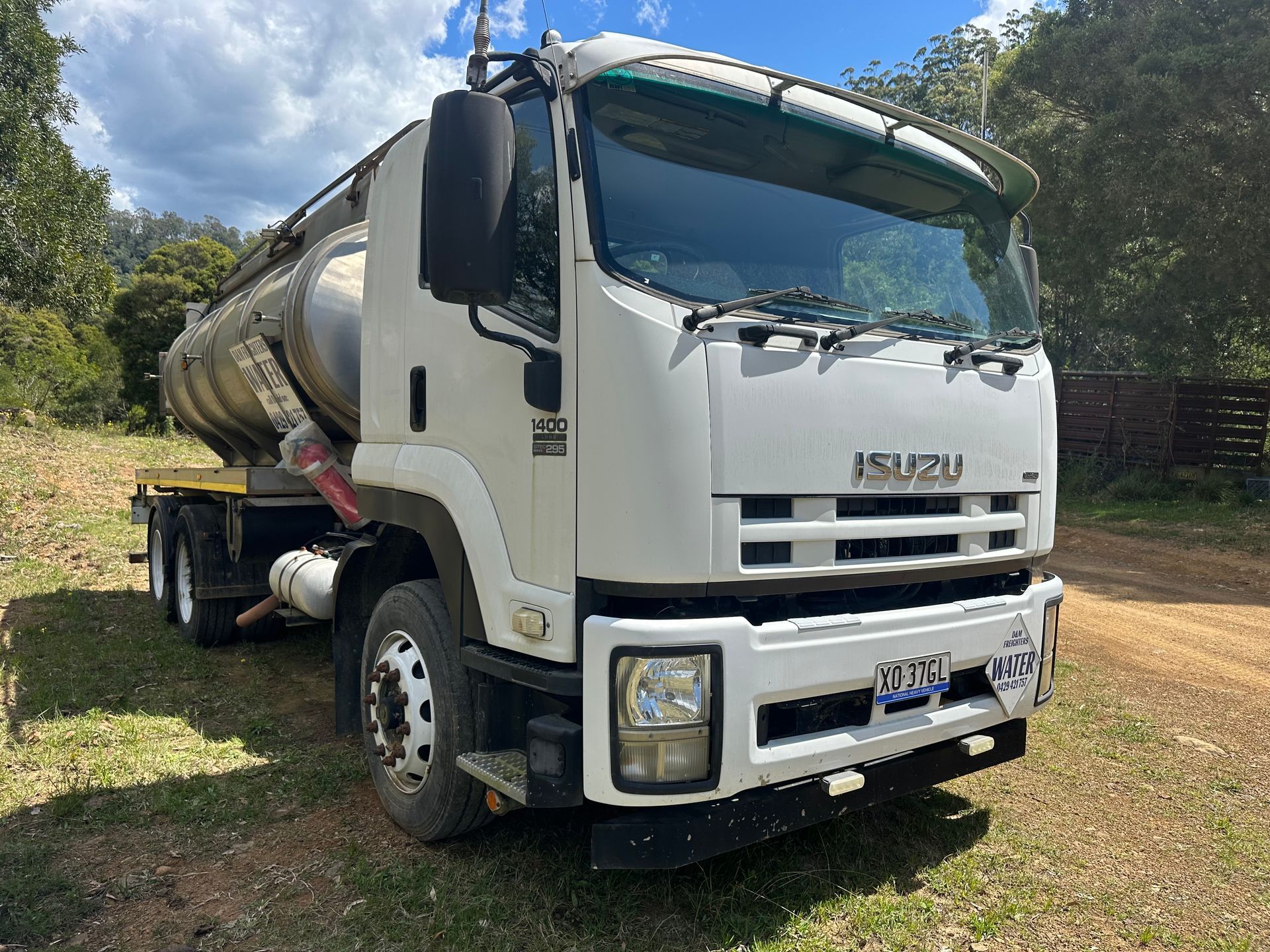 White Isuzu tanker truck parked outdoors on grass — D & M Freighters Water In Bucca Wauka, NSW