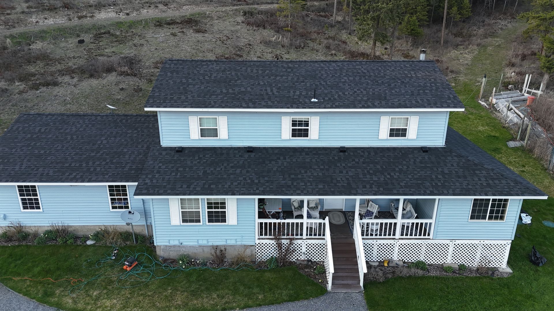 Blue two-story house with white trim and front porch, viewed from above.