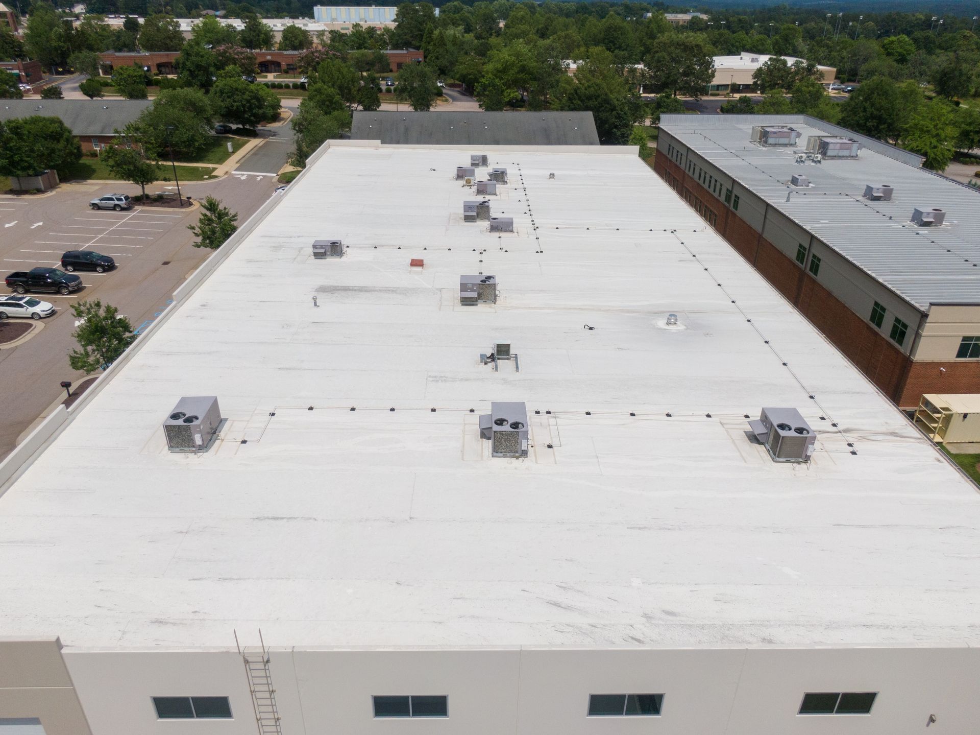 Roof with gray metal panels and a chimney, viewed from above near trees.