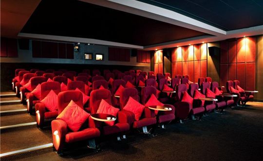 An empty movie theater with red chairs and tables