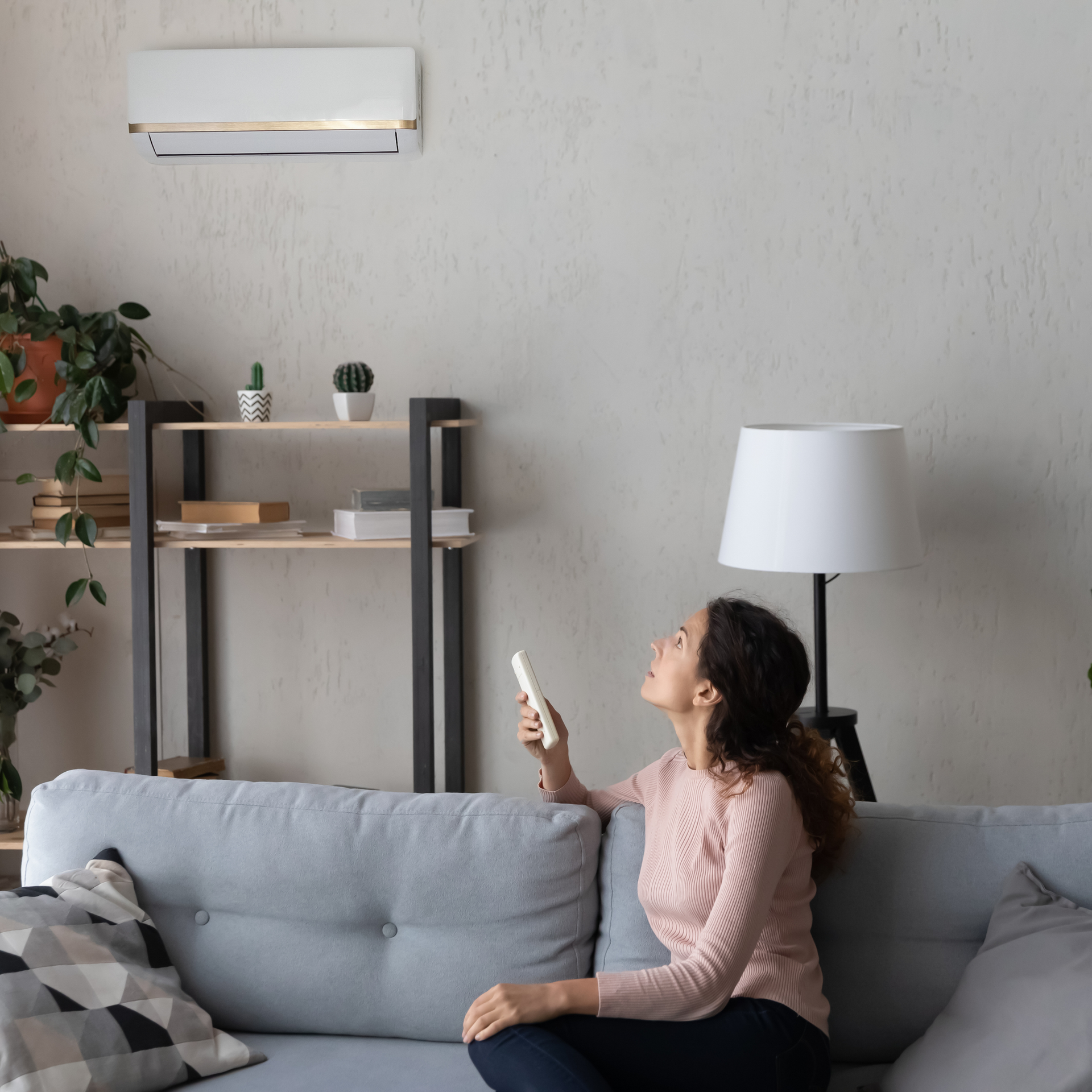 A woman is sitting on a couch holding a remote control.