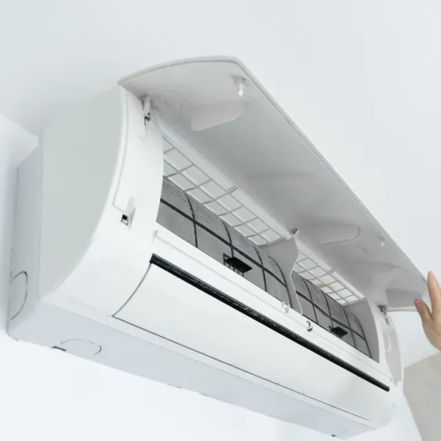 A person is opening the cover of an air conditioner.