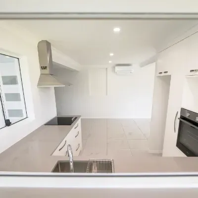 An empty kitchen with a sink and stove top oven