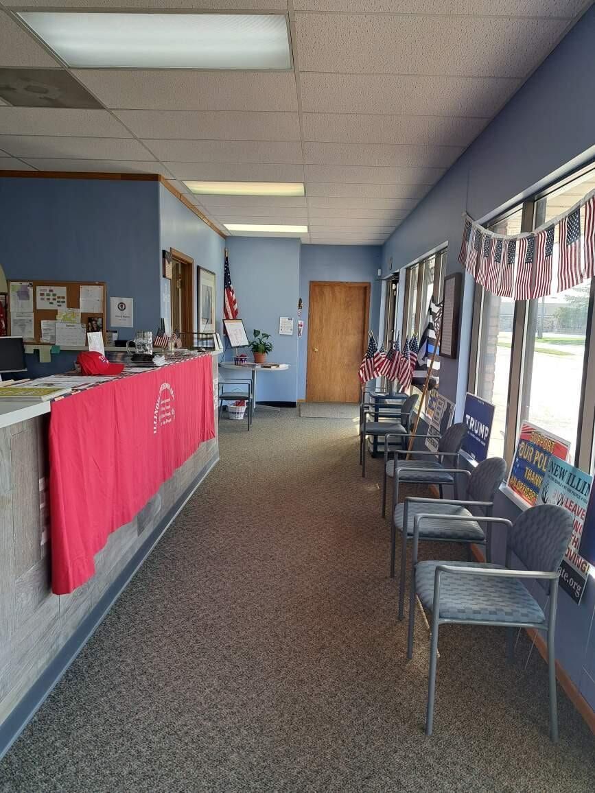Empty office waiting area with chairs, windows, and a red-draped reception counter