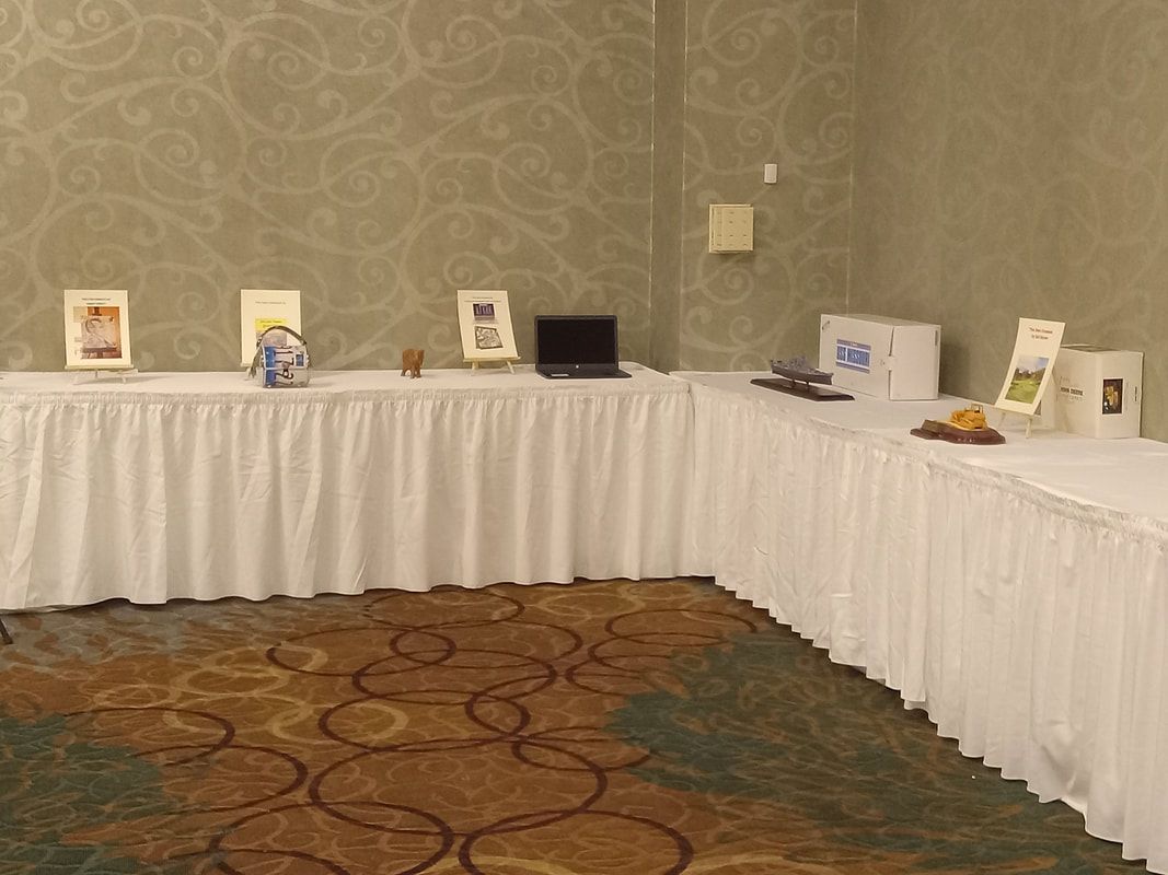 U-shaped table with white tablecloths displaying pamphlets and small items in a conference room