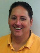 Smiling person in a yellow polo shirt against a plain background