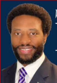Portrait of a smiling man in a dark suit and purple striped tie against a blue background