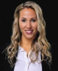 Portrait of a smiling blonde woman in a black blazer and white blouse against a dark background
