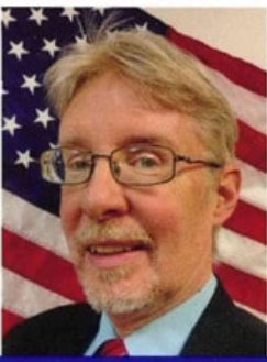 Portrait of a man in glasses and a suit before a waving American flag background