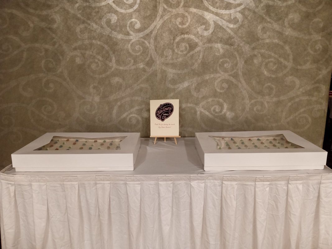 Two white trays on a draped table beneath a small sign, against a patterned wallpaper backdrop