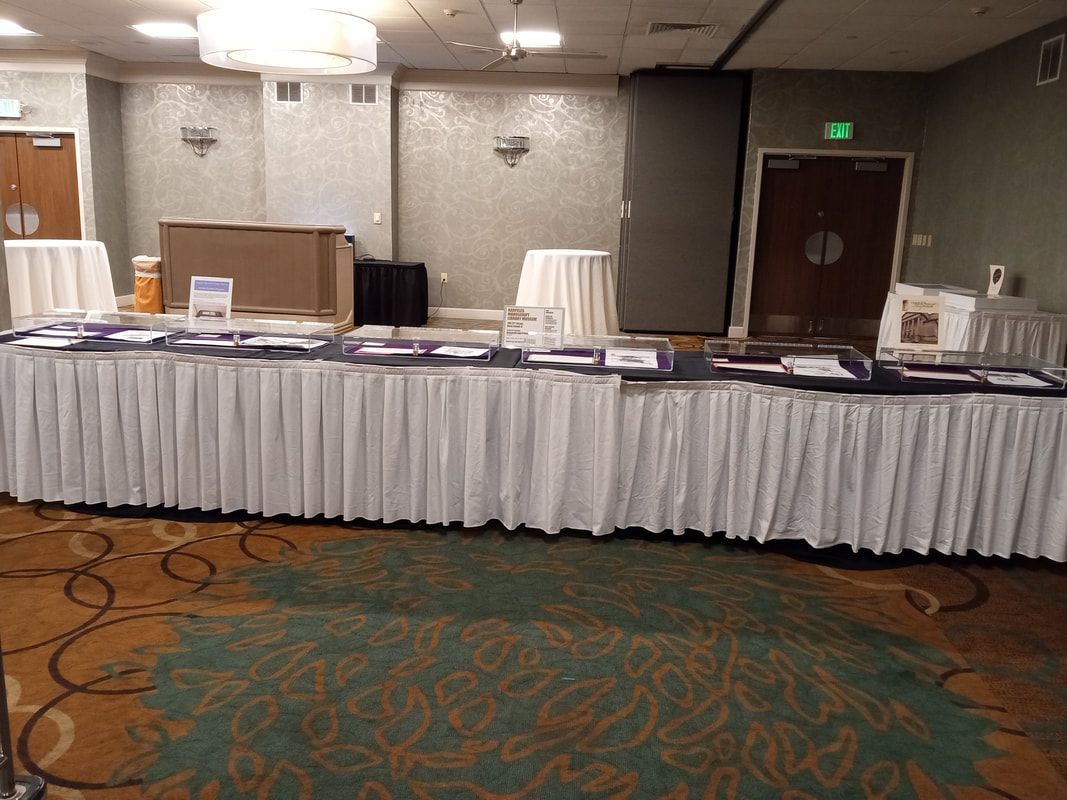 Banquet hall buffet table with white tablecloths, platters, and chairs along the wall