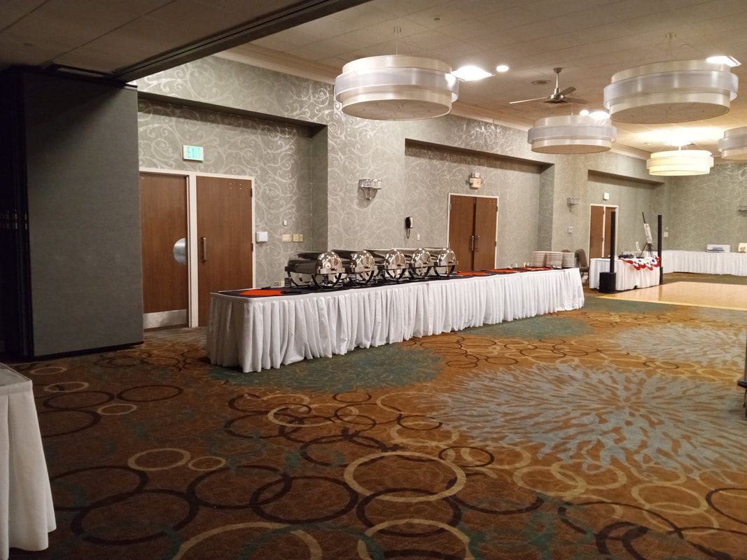 Hotel banquet hall with buffet tables, white tablecloths, and large round ceiling lights