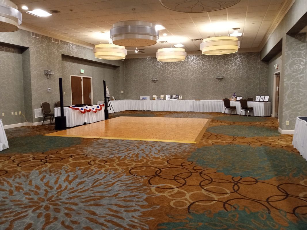 Empty hotel conference room with tables along the walls and patterned carpet on the floor