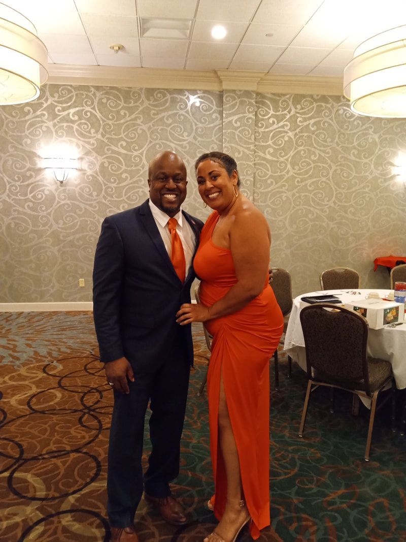 Two people smiling and posing together at a formal event in a banquet hall