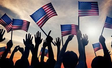 Silhouetted crowd waving American flags at a sunset rally