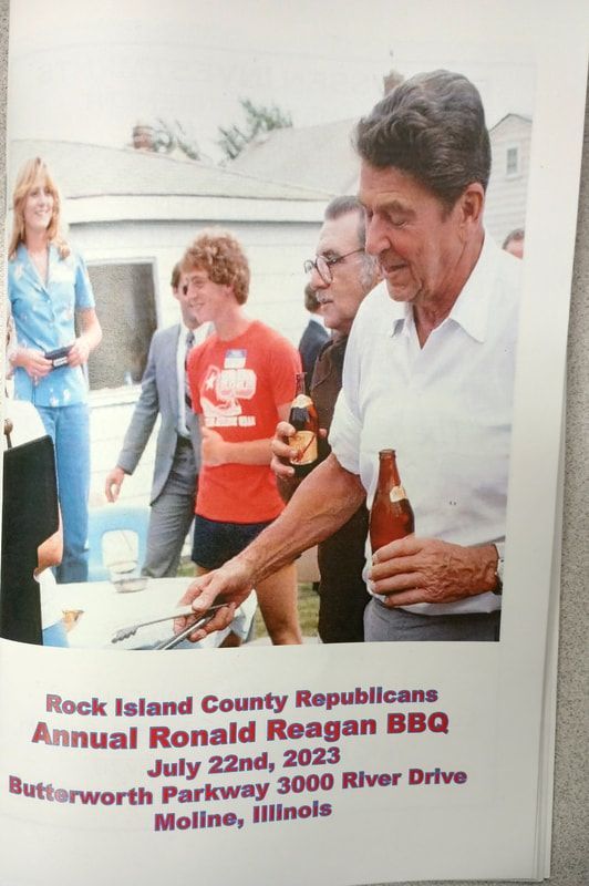 Reagan BBQ event with a man holding a beer and serving food at a buffet table, with people nearby