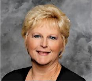 Portrait of a smiling woman with short blonde hair against a gray studio backdrop