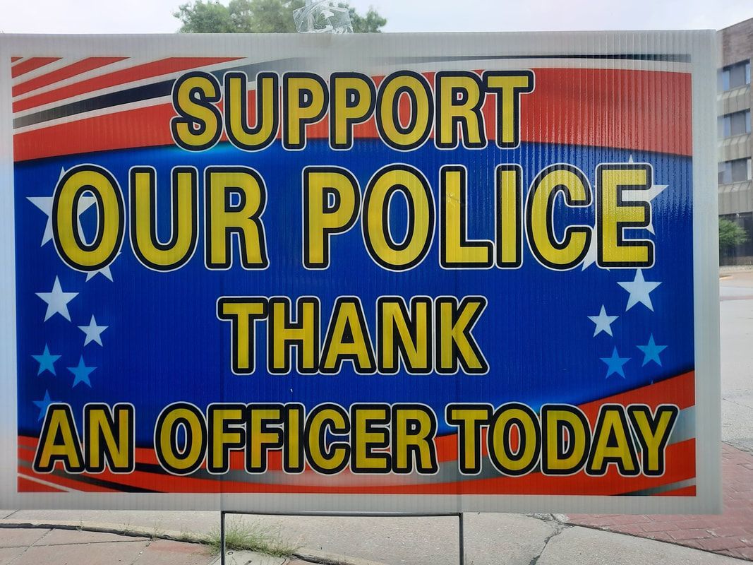 Blue and red sign reading “Support Our Police, Thank an Officer Today” with stars