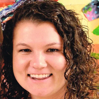 A woman with curly hair is smiling for the camera