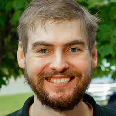 A man with a beard is smiling for the camera.