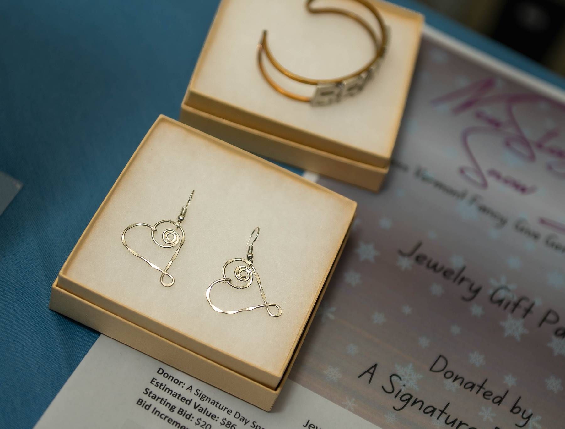Earrings and bracelet in gift boxes on a blue surface, part of a jewelry gift pack.