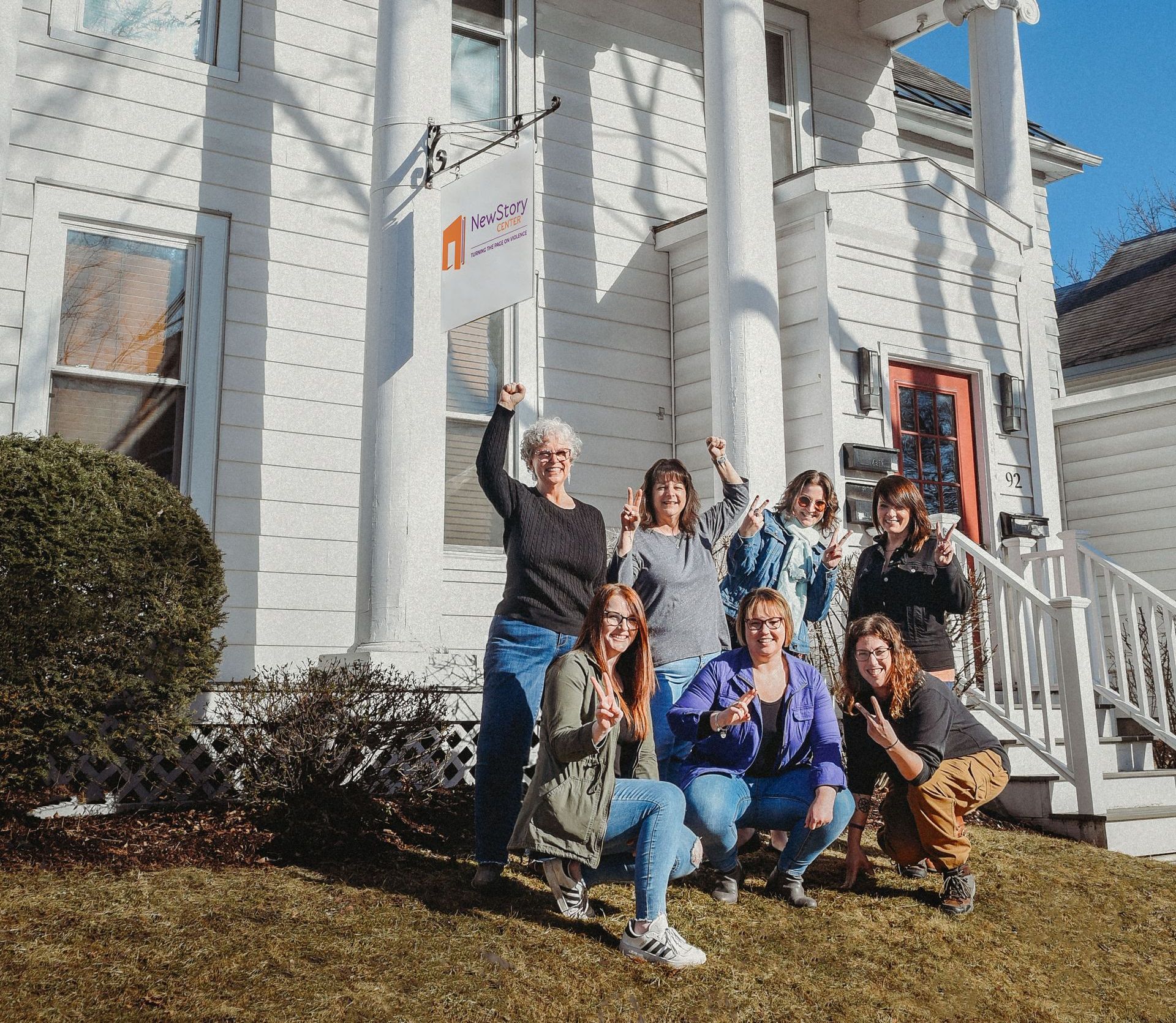 A group of people are posing for a picture in front of a white house.