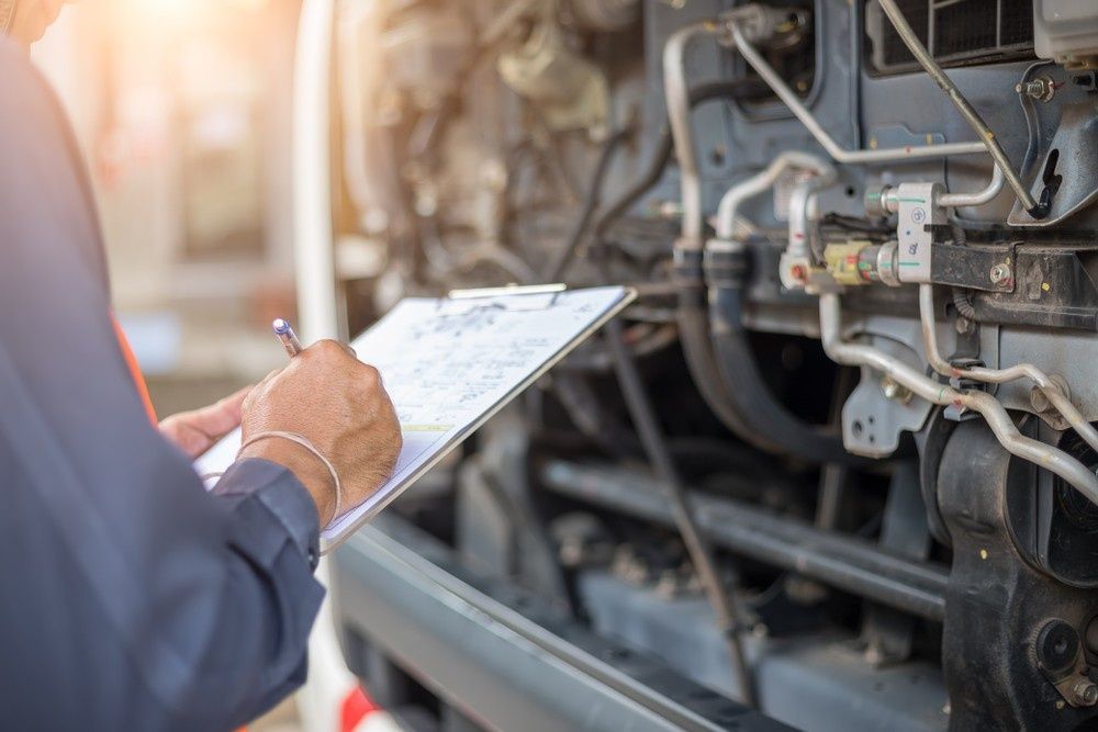 Mechanic Inspecting a Vehicle, Writing on A Clipboard with Engine Parts — S&P Complete Automotive in Port Macquarie, NSW
