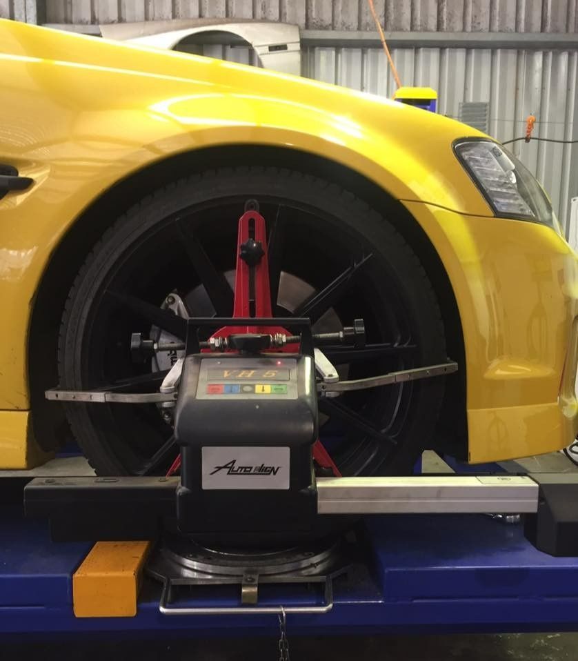 A Yellow Car's Front Wheel Being Aligned by A Machine in A Garage — S&P Complete Automotive in Port Macquarie, NSW