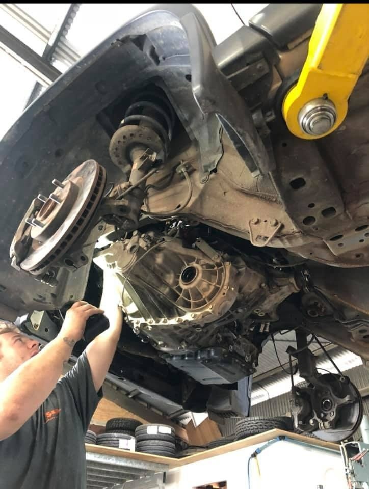 Mechanic inspecting underside of a car lifted on a hoist in a garage — S&P Complete Automotive in Port Macquarie, NSW.