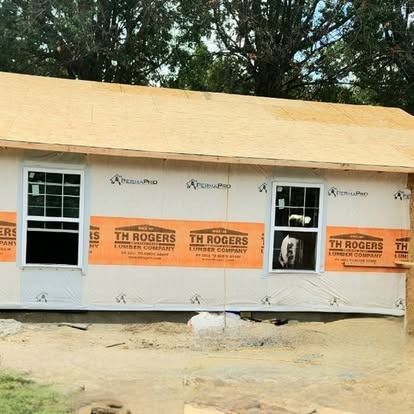 Partially built beige house with orange Tyvek wrap and windows installed