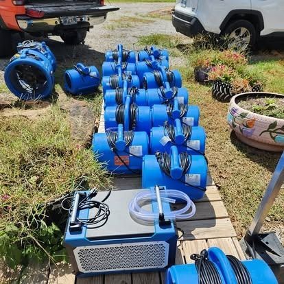 Blue irrigation pipes and fittings arranged on grass beside vehicles, with a small pump in front.
